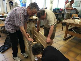 Männer bauen in einer Holzwerkstatt einen Hochbeetkasten