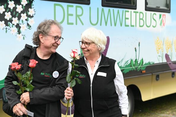 Mann und Frau mit Rosen vorm Umweltbus Lumbricus